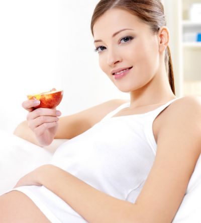 Kobieta w ciąży je jabłko